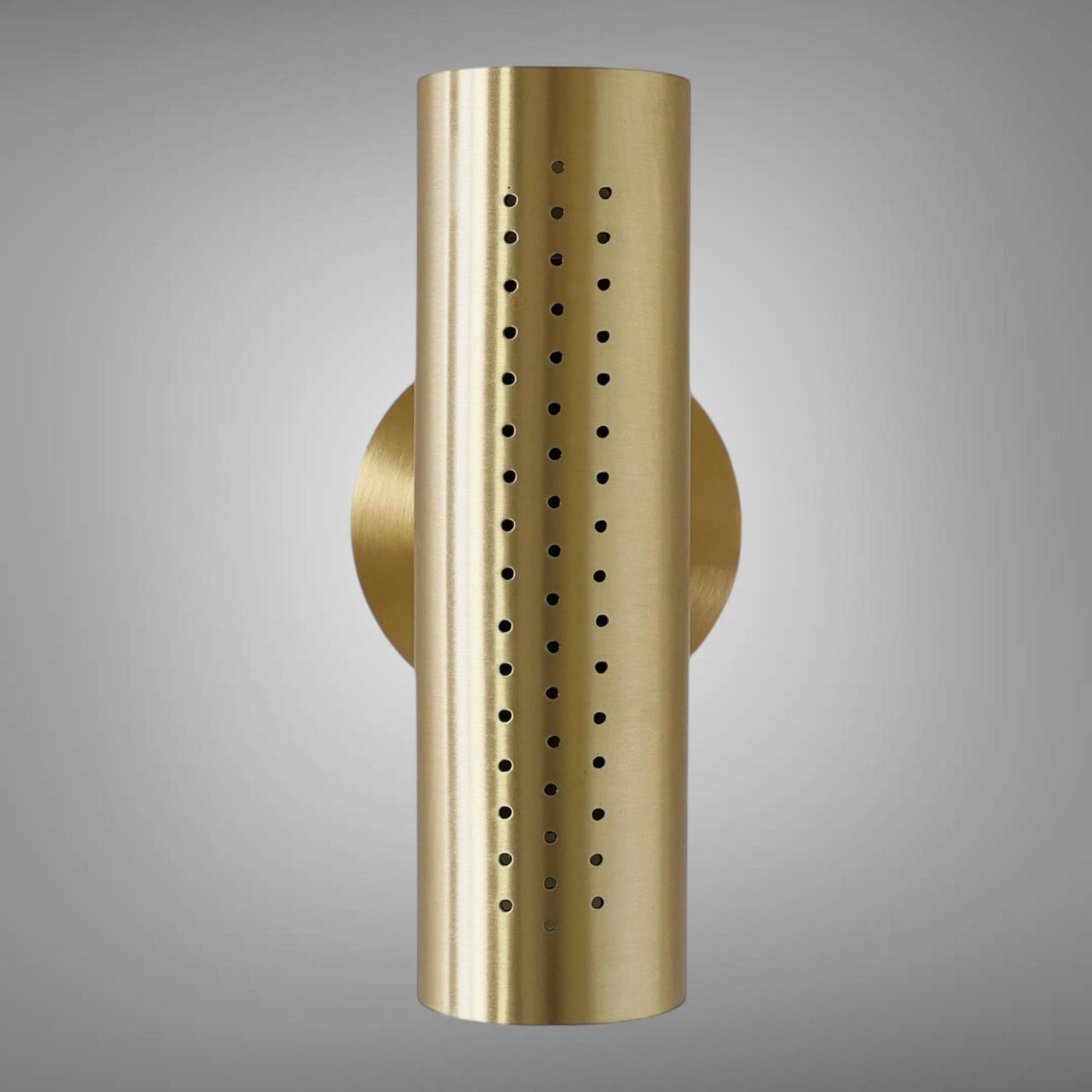 Front view of perforated brass cylinder wall sconce with round backplate on a gray background.