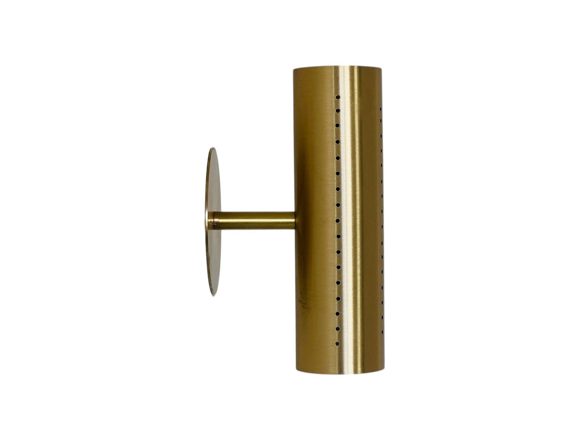 Side profile of perforated brass cylinder wall sconce showing the arm and round wall backplate on a white background.