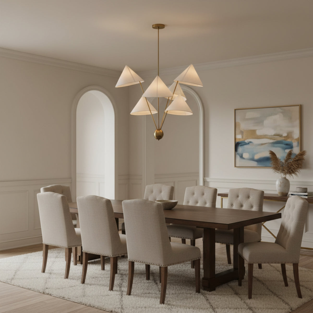 Perth 5 light sculptural chandelier shown illuminated with warm light through cream cone shades and an elegant brass-tone frame.