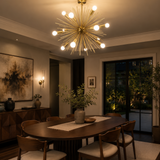 Provence 8 light brass tone starburst Sputnik chandelier illuminated above a modern dining table in a warm contemporary interior.