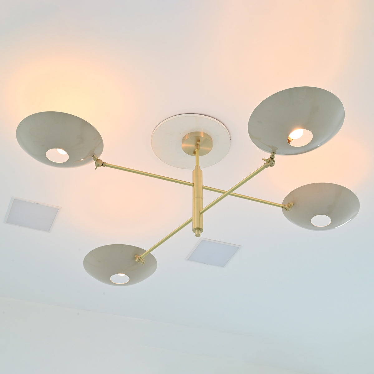 Underside perspective of Queenstown 4-light chandelier showcasing four shallow bowl shades, slender brass-tone arms and sculptural geometric design.
