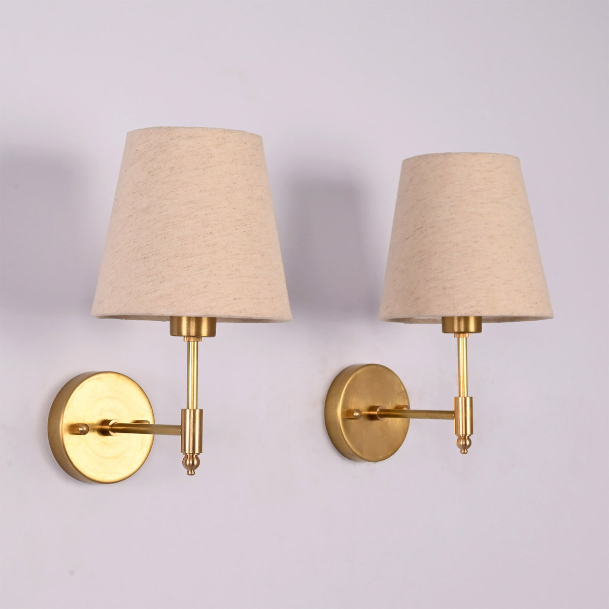 Rear angled view of the Milan brushed brass wall sconce featuring a natural linen fabric shade and round wall backplate.