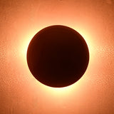 Circular red wall light glowing with strong backlit halo effect on textured wall surface