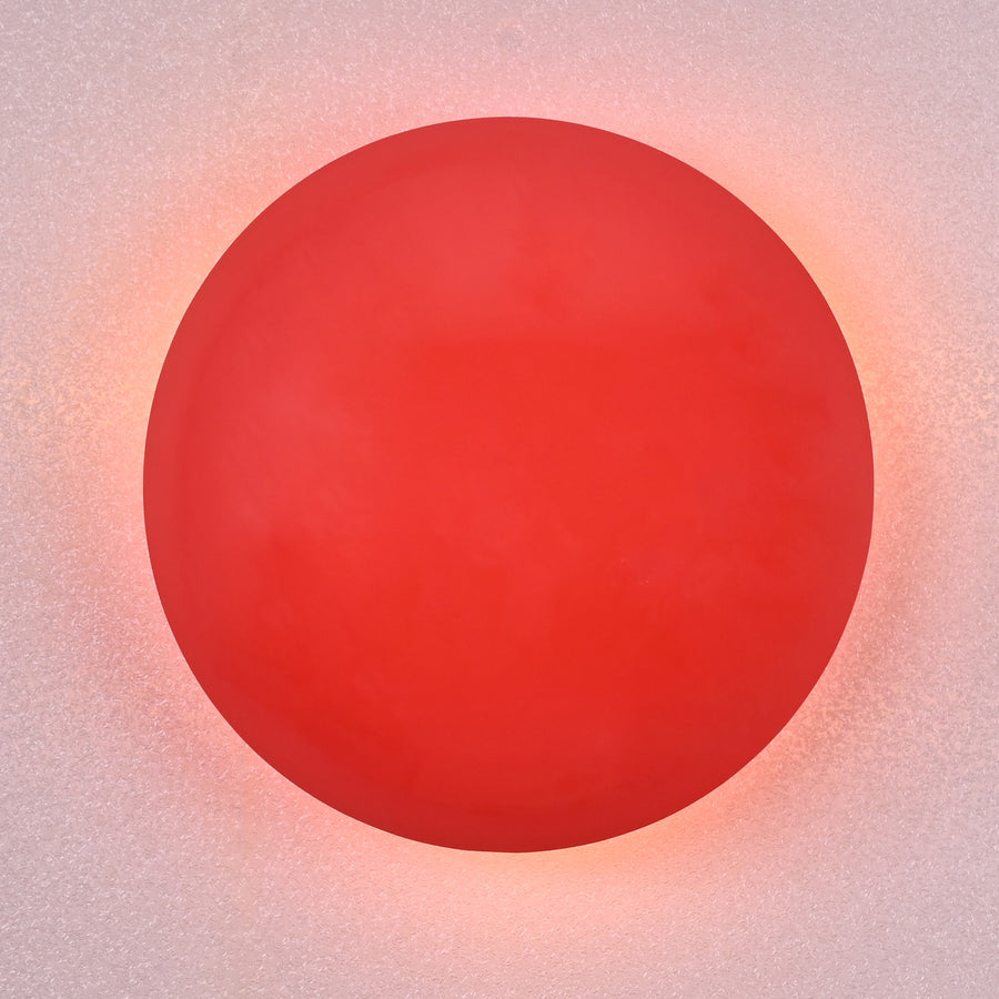 Modern red circular wall sconce with soft glowing ambient halo, handmade brass design