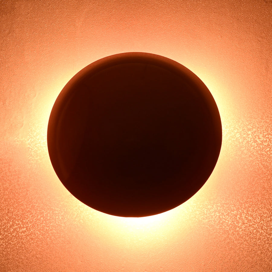 Modern red circular wall sconce with soft glowing ambient halo, handmade brass design