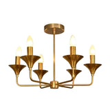 Rouen 6 light brass chandelier illuminated with warm candle-style bulbs and sculptural flared metal details.