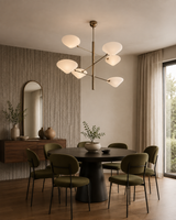 Saint Tropez 6 light sculptural chandelier illuminating a contemporary dining room with a round table and modern seating.