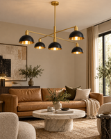 San Sebastian 5 light black dome chandelier with brass-tone frame illuminated above a warm contemporary living room.