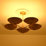 Low-angle view of Savannah 5-light sculptural brass chandelier showcasing curved gold saucer shades, radial metal arms, and warm golden ceiling illumination.
