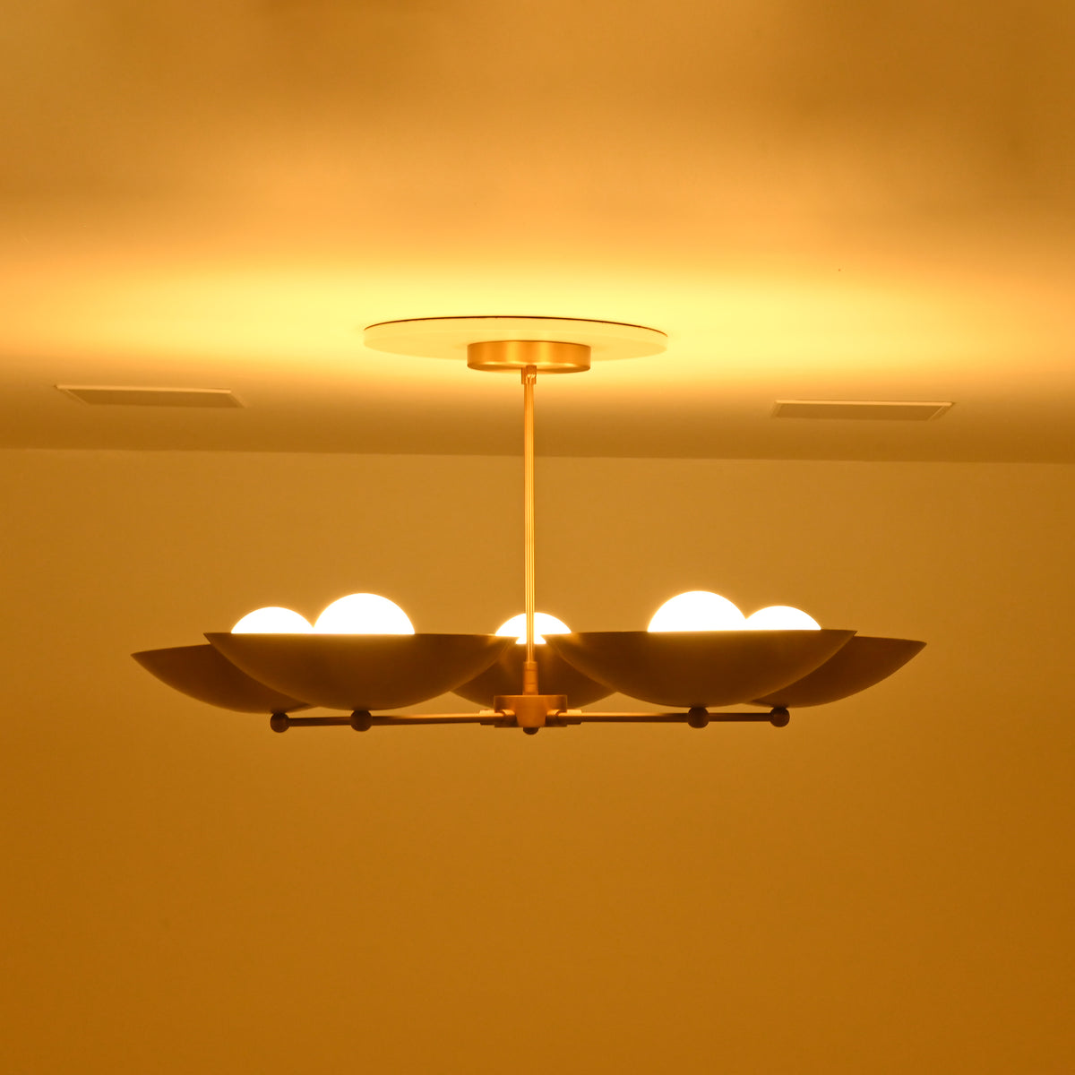 Wide side profile of Savannah 5-light gold bowl chandelier displaying its horizontal radial arm arrangement, shallow saucer shades, and glowing bulbs.