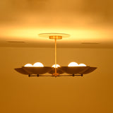 Wide side profile of Savannah 5-light gold bowl chandelier displaying its horizontal radial arm arrangement, shallow saucer shades, and glowing bulbs.