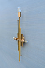 Side angled view of brass wall sconce with vertical rods and three bulb holders, elegant modern wall lighting fixture.