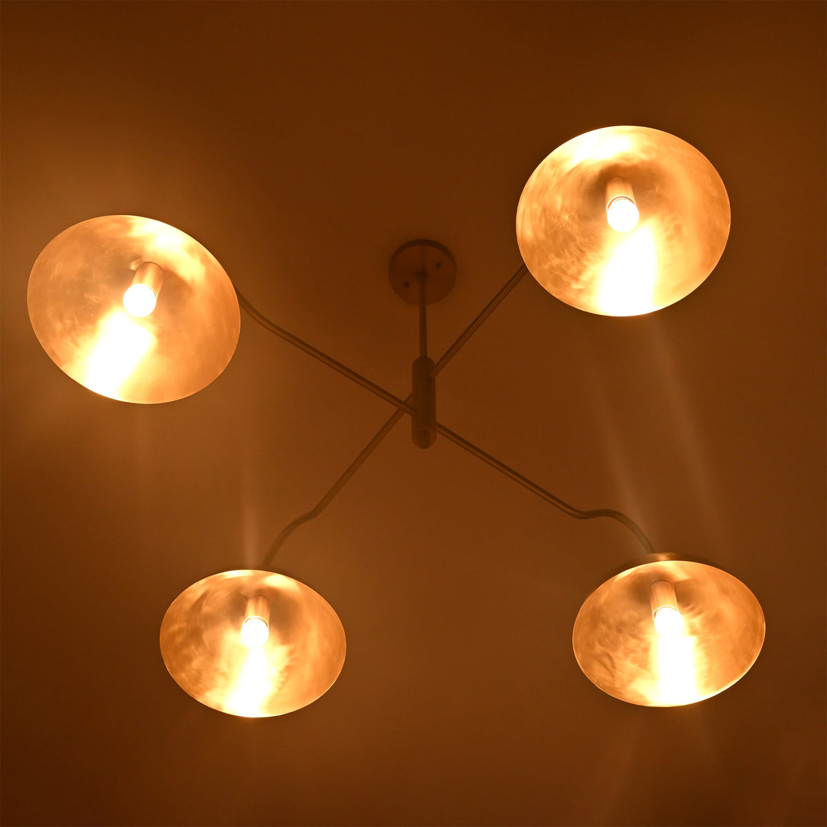 Siena Curved Arm chandelier shown illuminated, creating warm ambient light through sculptural dome shades.