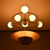 Siena Globe Disc Chandelier illuminated with six round globes, warm ambient glow, and bold lower disc detail.