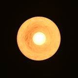 Illuminated brass pendant light viewed from below showing circular warm ambient glow