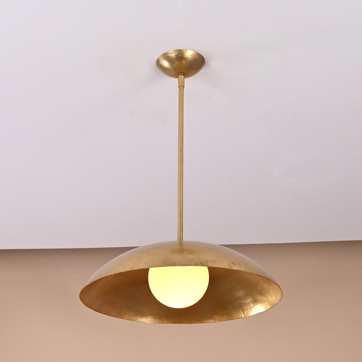 Modern brass pendant lamp featuring dome-shaped shade and warm upward glow, handmade lighting design