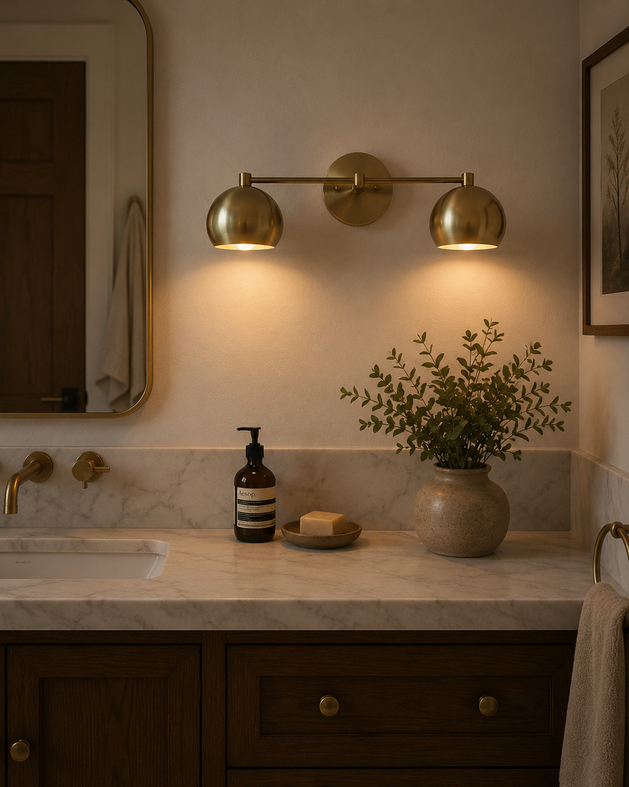 Sloane 2 light double dome brass wall sconce installed above a bathroom vanity with warm ambient lighting – Model 32811