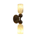 Front angled view of the Sloane Dual Alabaster Globe Wall Sconce featuring two illuminated natural alabaster cylinder shades with solid brass sphere accents and a round brass wall canopy