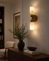 Sloane Dual Alabaster Globe Wall Sconce installed in a contemporary living room, casting warm ambient light above a wooden console with decorative accessories and modern furnishings.