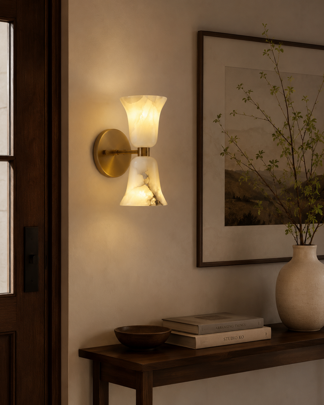 Sloane Hourglass Alabaster Wall Sconce installed in a modern entryway, providing warm ambient lighting with handcrafted alabaster shades and solid brass detailing.