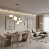 Angled view of Sloane 5 light chandelier with opal glass shades arranged around a linear brass frame.