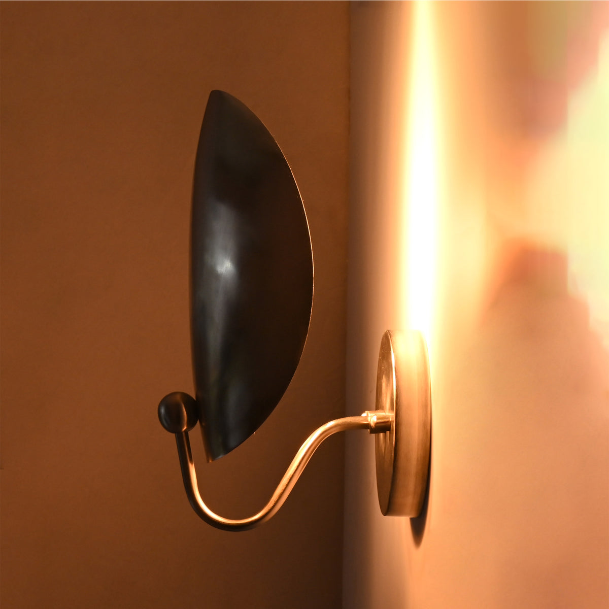 ide illuminated view of the Sloane Modern Oval Shield Wall Sconce revealing the concealed light source and warm indirect wall wash effect.