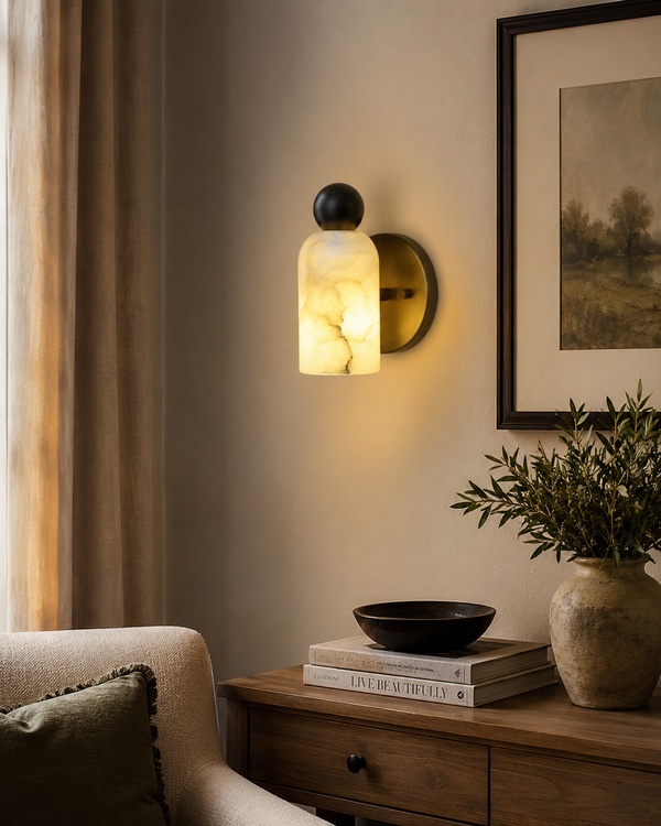 Sloane Rounded Alabaster Wall Sconce installed in a contemporary living room, providing warm ambient lighting beside a wooden console and neutral décor.