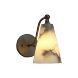 Angled view of the Sloane tapered alabaster wall sconce highlighting the curved brass arm, natural alabaster cone shade, and warm ambient illumination.
