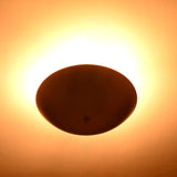 Brass flushmount light producing soft halo effect on ceiling in warm golden tones