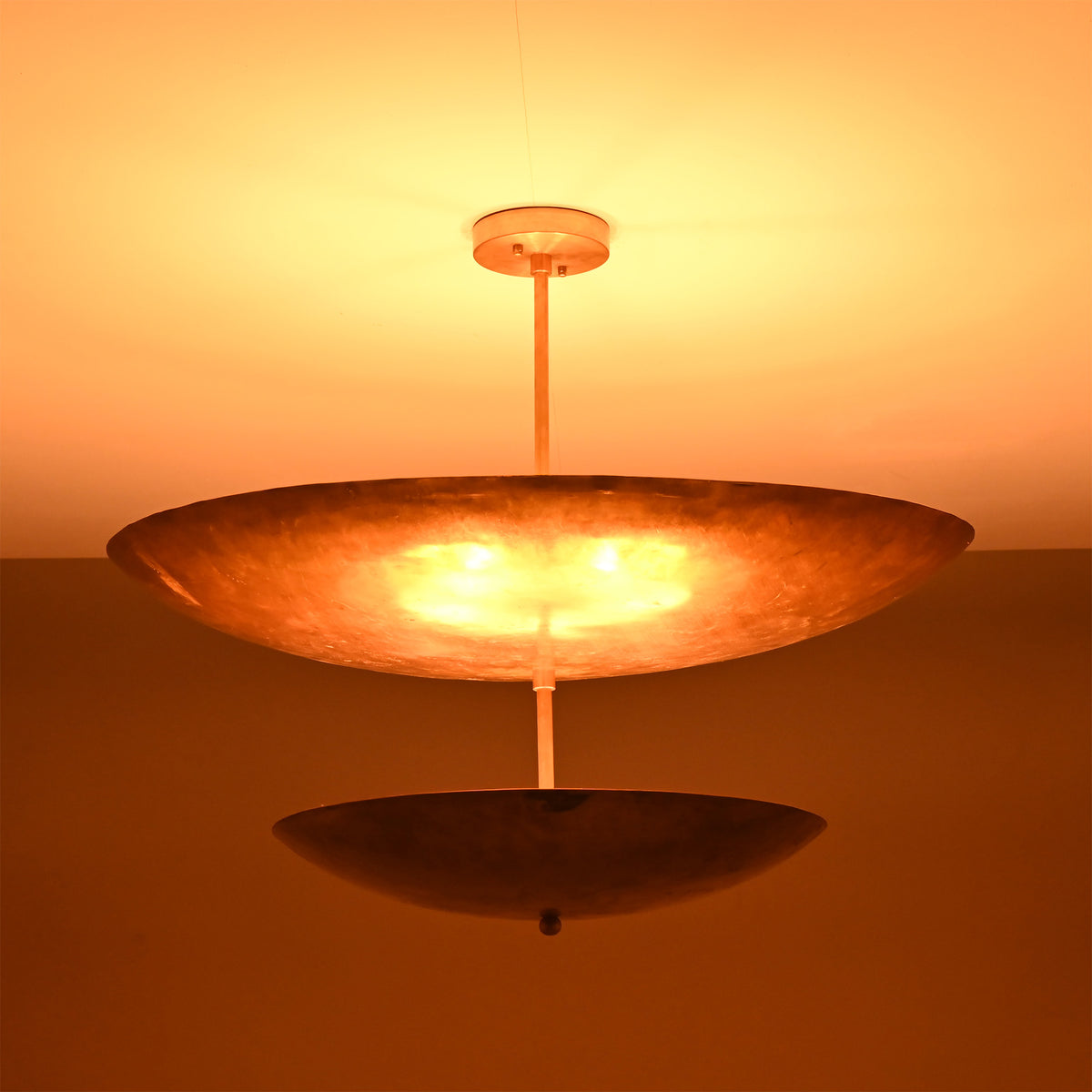 Solara Double Saucer Pendant Light glowing warmly in low light with dramatic layered illumination effect.