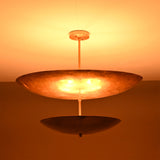 Solara Double Saucer Pendant Light glowing warmly in low light with dramatic layered illumination effect.