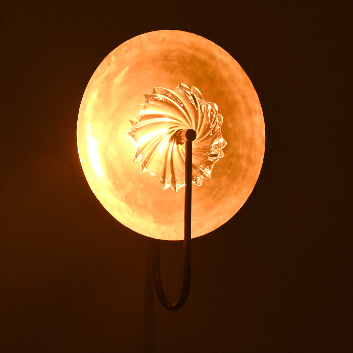 Angled illuminated view of Solara halo glass disc wall sconce creating a rich warm decorative halo.