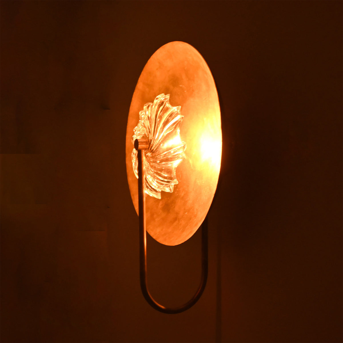 Side illuminated view of Solara halo glass disc sconce with warm glow through textured glass center.