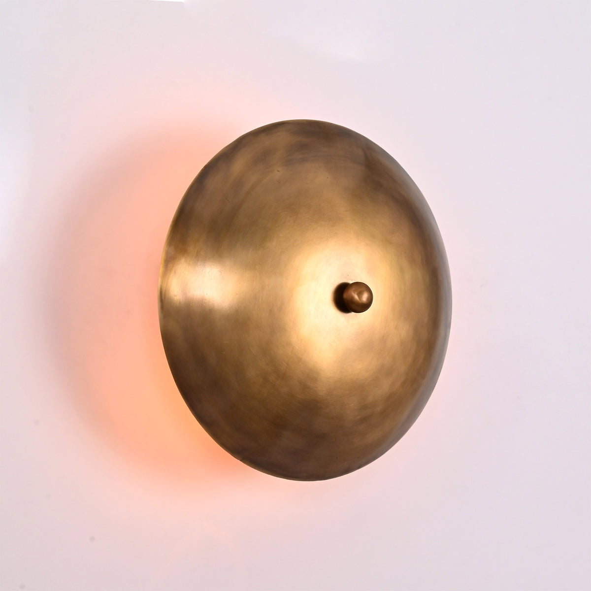Close up of Solene Shield Wall Sconce highlighting sculptural round disc form and warm wall glow.