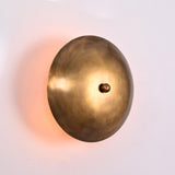 Close up of Solene Shield Wall Sconce highlighting sculptural round disc form and warm wall glow.