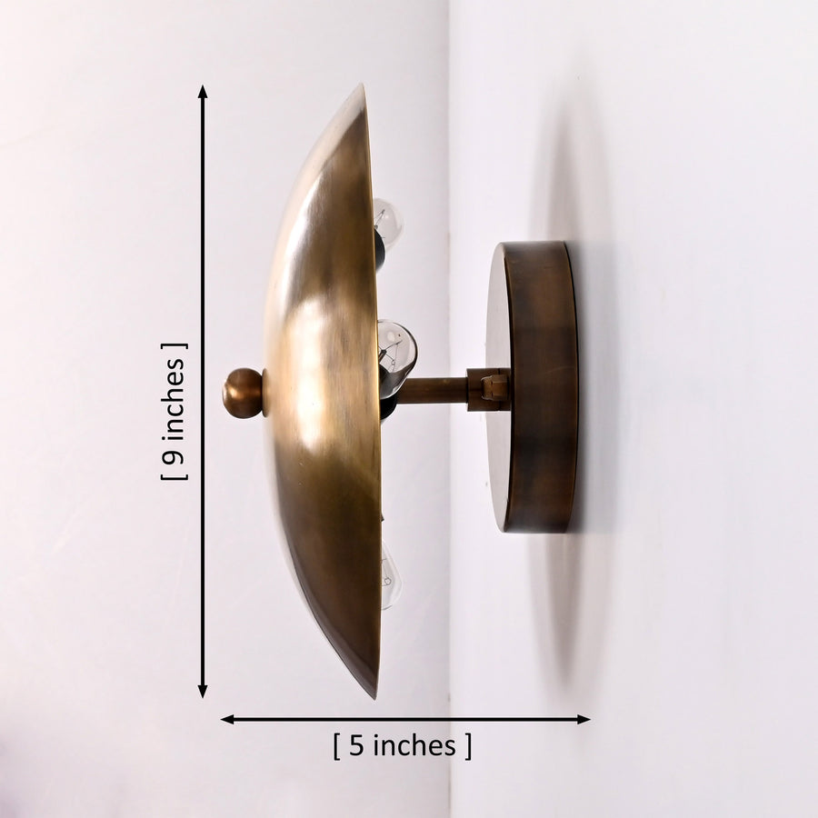 Solene Shield Wall Sconce installed in a cozy living room beside fireplace, shelves, and lounge chair.