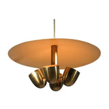 Sonoma 4 light disc chandelier shown illuminated from below with warm light reflecting across the cream shade and brass-tone bowl details.