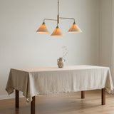 Sorrento 3 light brass chandelier with natural linen cone shades shown illuminated with a warm ambient glow.