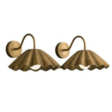 Angled view of two handcrafted brass pleated dome wall sconces with curved wall arms and softly scalloped shades.