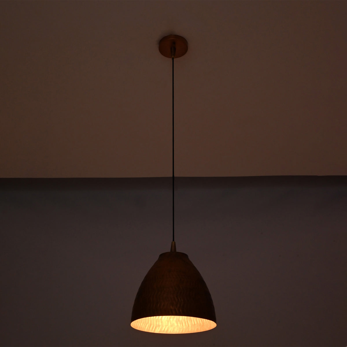 Hanging Sutton hammered bell pendant light with handcrafted copper shade and adjustable cord, providing warm task and ambient illumination.