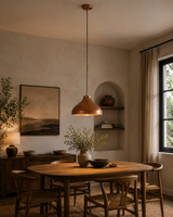 Sutton hammered copper dome pendant light installed above a wooden dining table in a modern farmhouse dining room with warm ambient lighting.