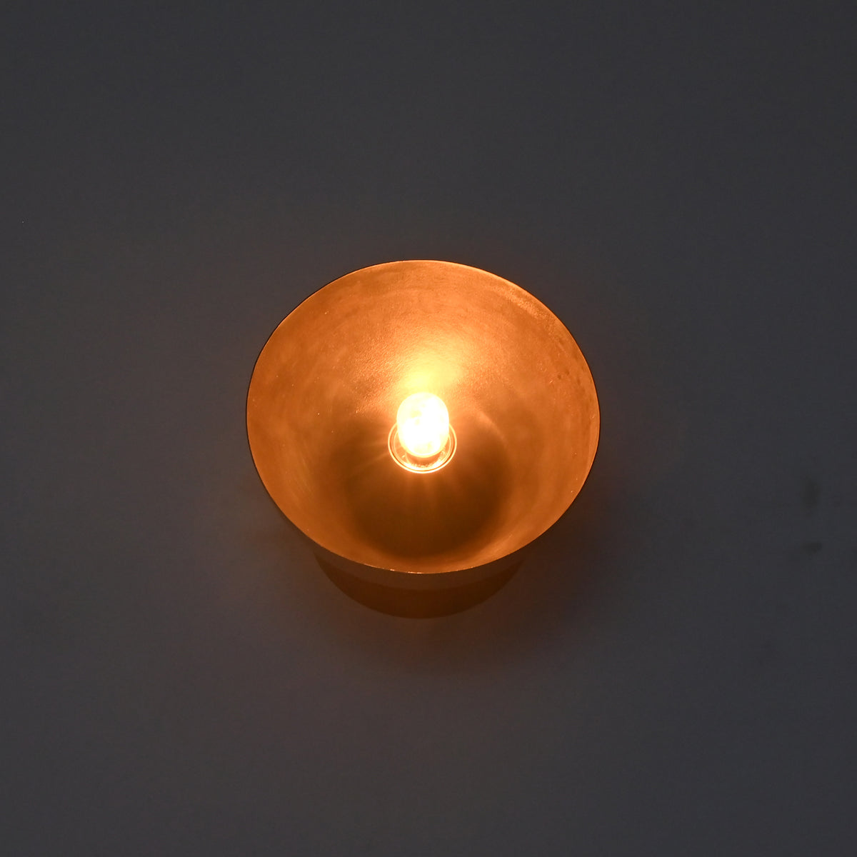 Illuminated close-up of the Sutton Modern Dome Wall Sconce producing a warm ambient glow from the exposed bulb within the dome shade.