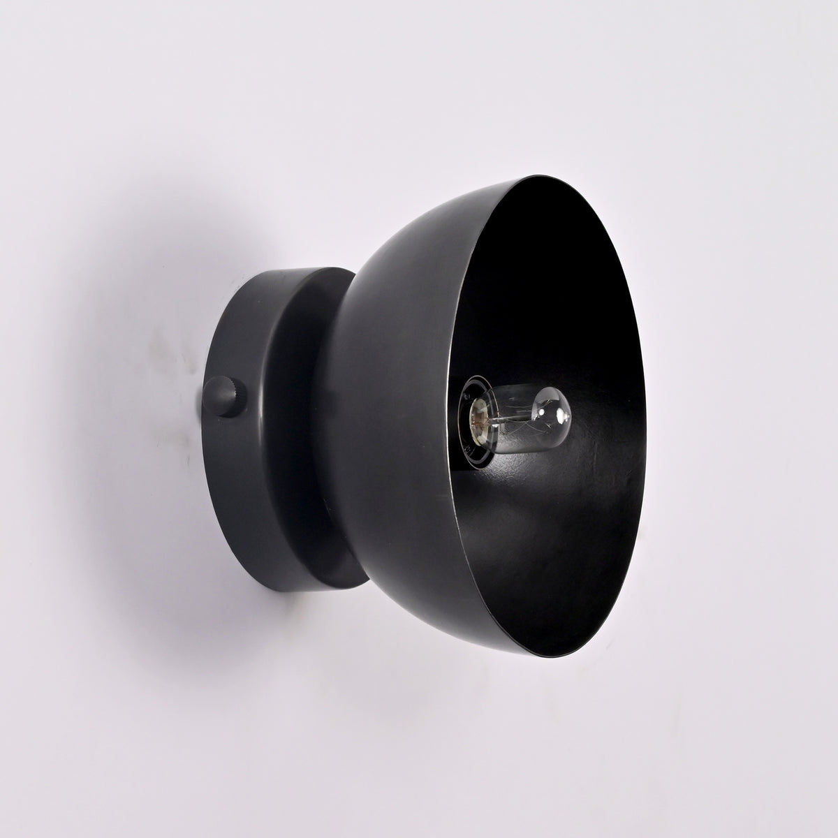 Perspective detail of the Sutton Modern Dome Wall Sconce highlighting the smooth handcrafted dome shade and exposed bulb socket.