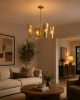 Sutton perforated wrap linear chandelier installed in a contemporary living room, casting a warm ambient glow with its four perforated brass shades.