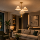 Sydney 3 light cream cone shade chandelier illuminated in a sophisticated modern living room with warm ambient lighting.