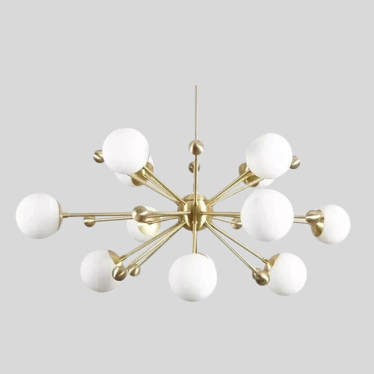 Angled view of Tallinn 12 light chandelier with white globe shades, brass-tone branching arms and sculptural central hub.