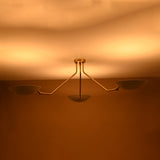 Contemporary three-light brass chandelier emitting soft indirect lighting with white enamel shades