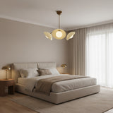 Toledo 3 light chandelier shown from a lower angle featuring sculptural cream disc shades, opal globe diffusers, and aged brass details.