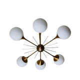 Toledo 6 light sculptural globe chandelier shown from below with six opal glass globes arranged around a brass-tone starburst central hub.