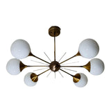 Toledo 6 light starburst globe chandelier shown from the front with opal glass globes, brass-tone radial arms, and a sculptural central hub.